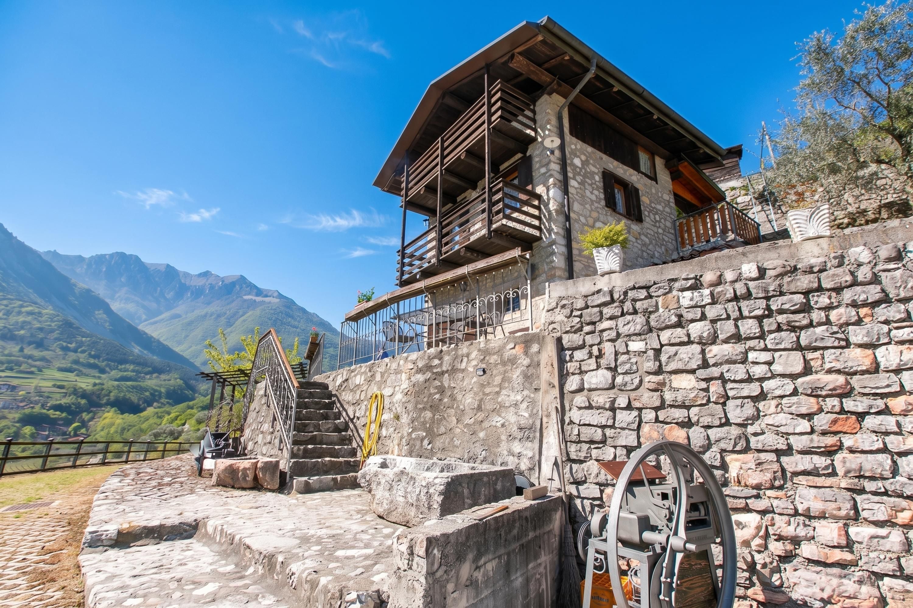 Un edificio de piedra con un balcón de madera, una escalera de piedra y una rueda hidráulica.