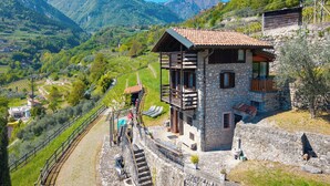 A stone building with a balcony, a staircase, and a view of a mountainous landscape. - Private Green Oasis - Terrace (Tenno)