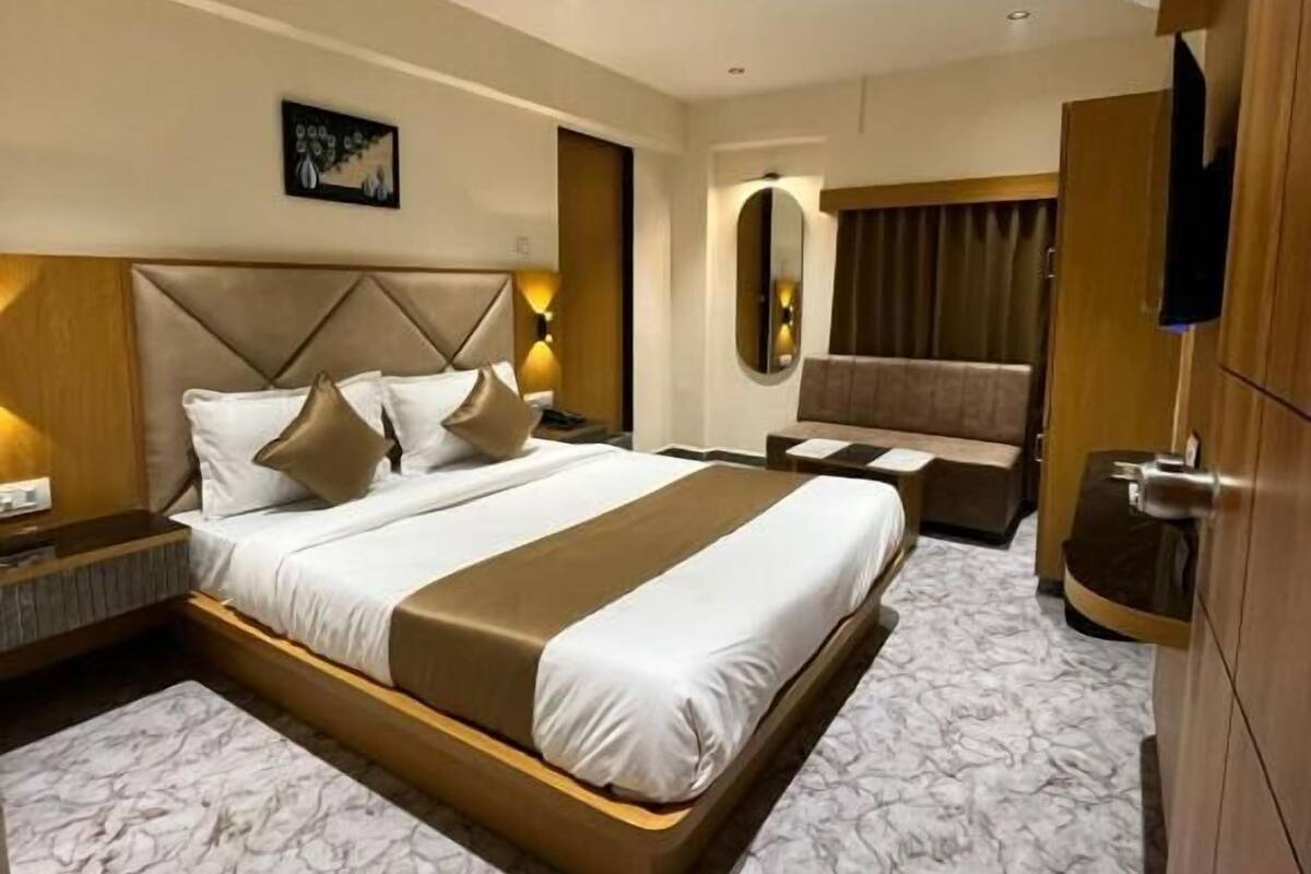 A hotel room with a large bed, a ceiling fan, a TV, and a marble-patterned floor.