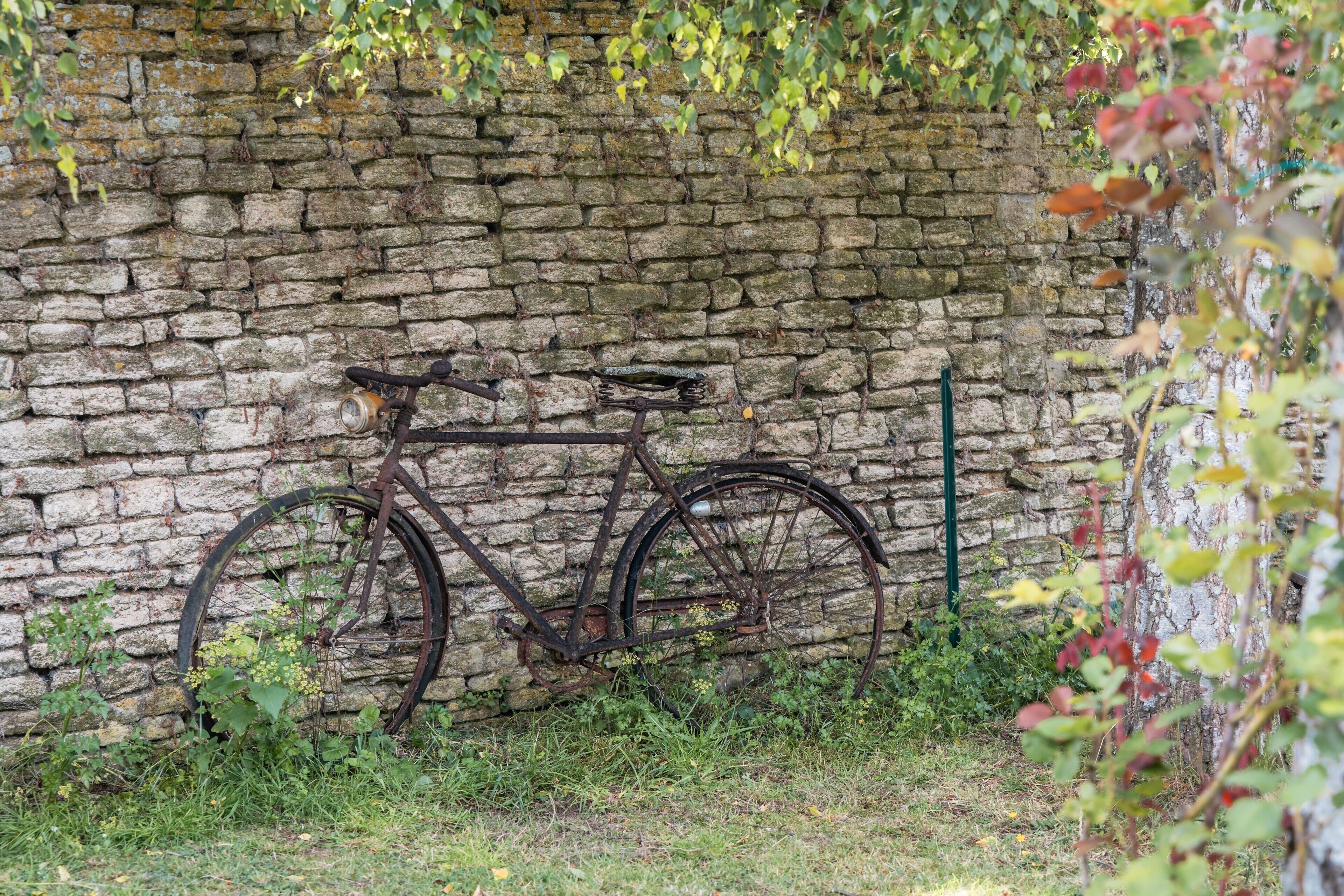 A rustic stone wall with a vintage bicycle leaning against it.