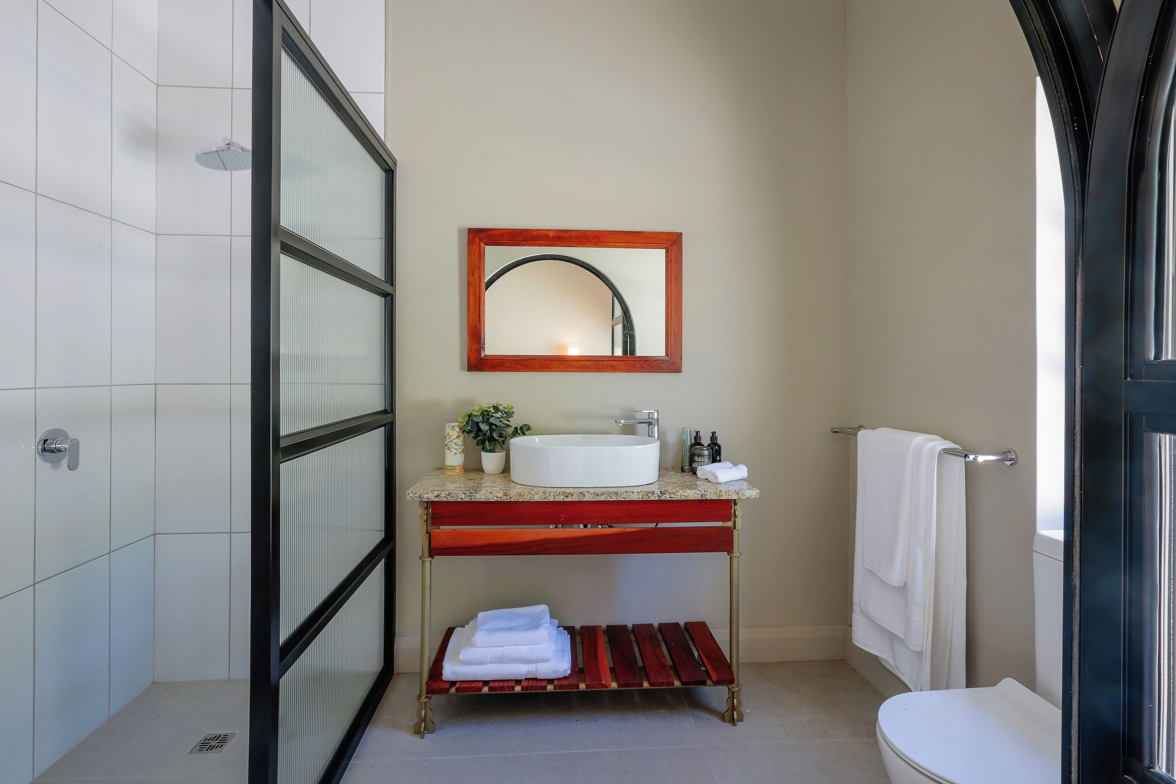 A bathroom with a white sink, a mirror, a towel rack, and a shower area.