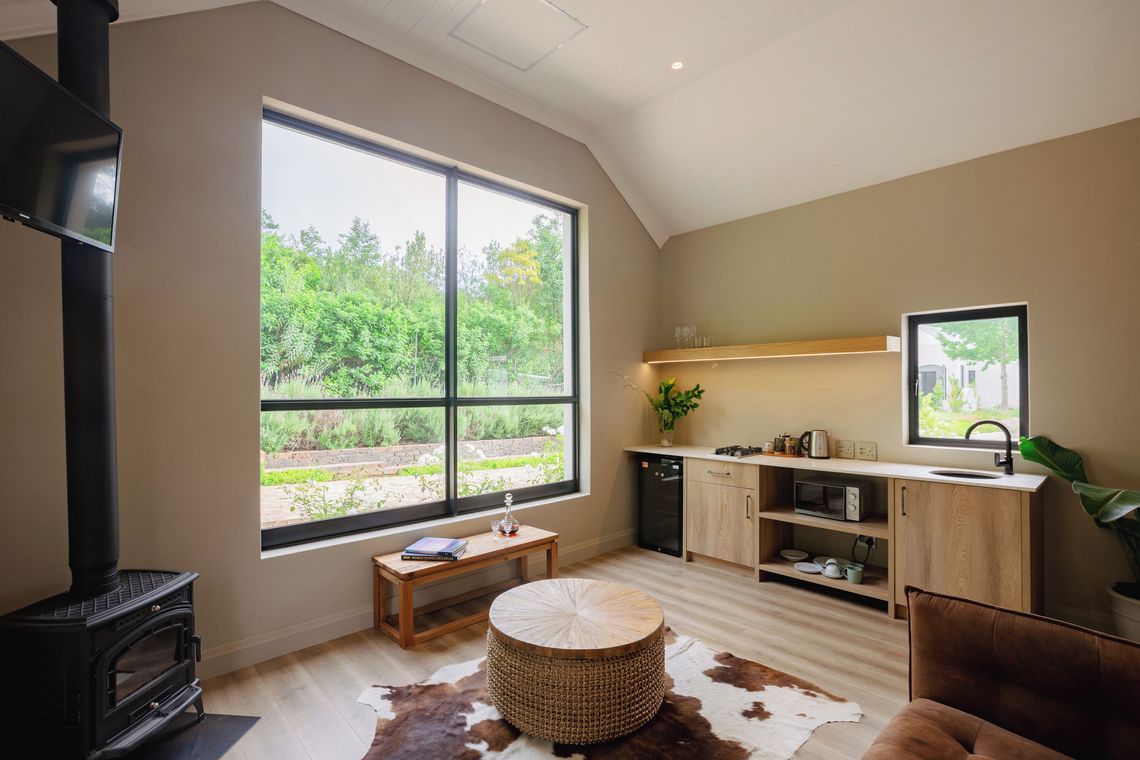 A modern kitchen with a large window, a wood-burning stove, and a dining area with a cowhide rug.