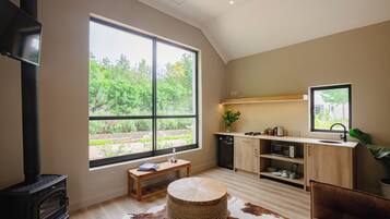 A modern kitchen with a large window, a wood-burning stove, and a dining area with a cowhide rug.