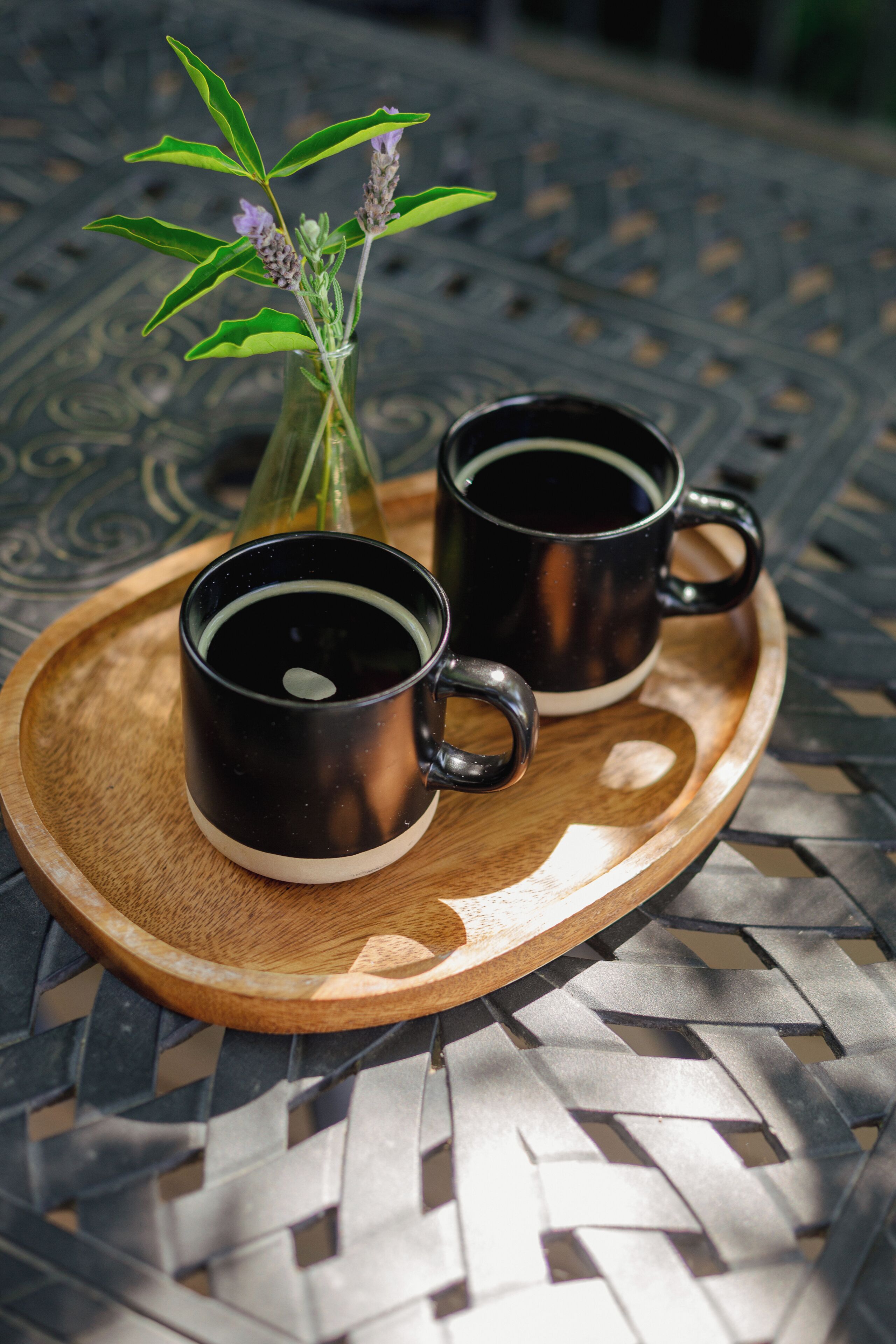 Two black mugs on a wooden tray.