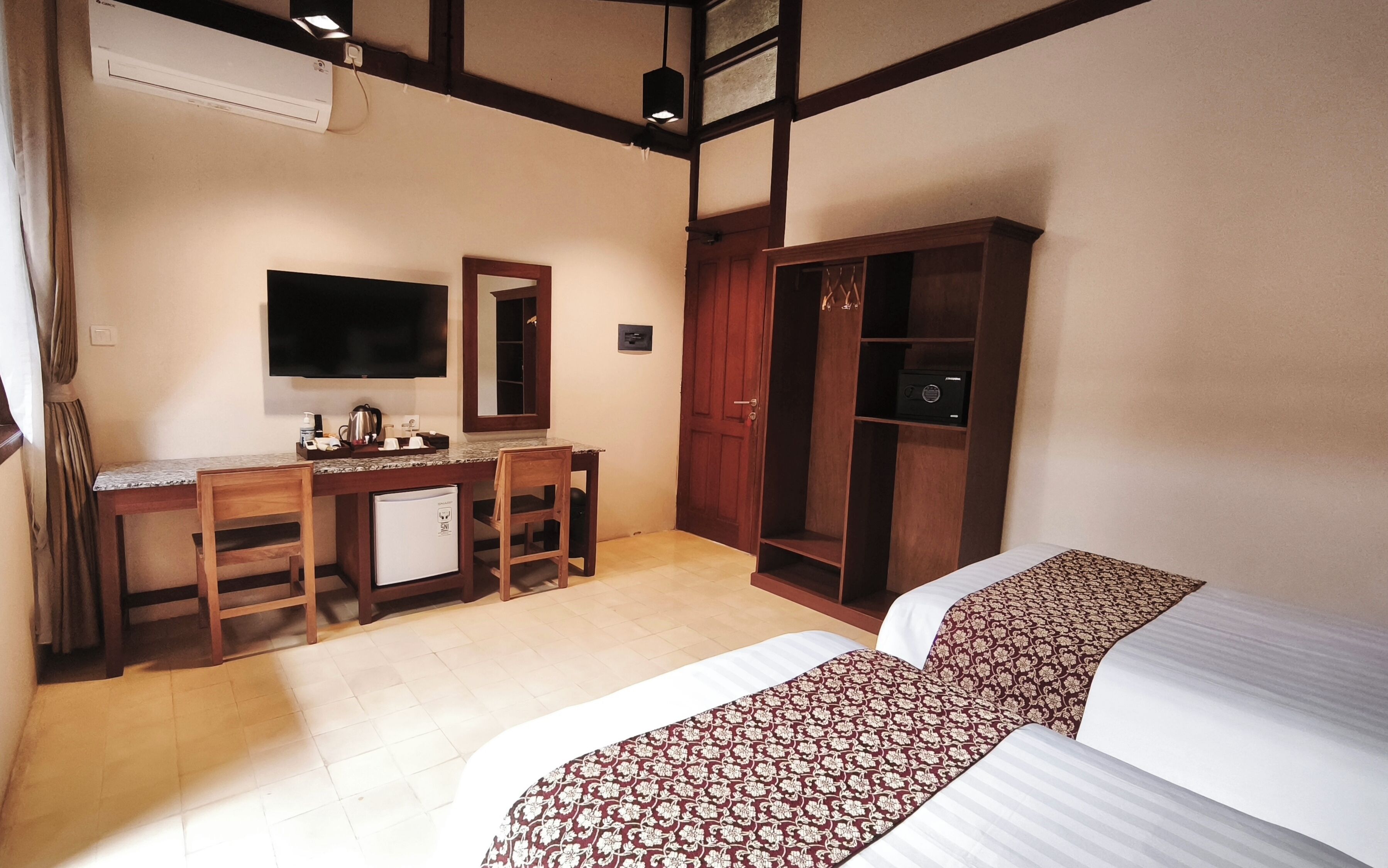 Una habitación de hotel con escritorio, televisor, armario y dos camas.