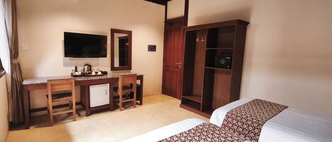 Una habitación de hotel con escritorio, televisor, armario y dos camas.