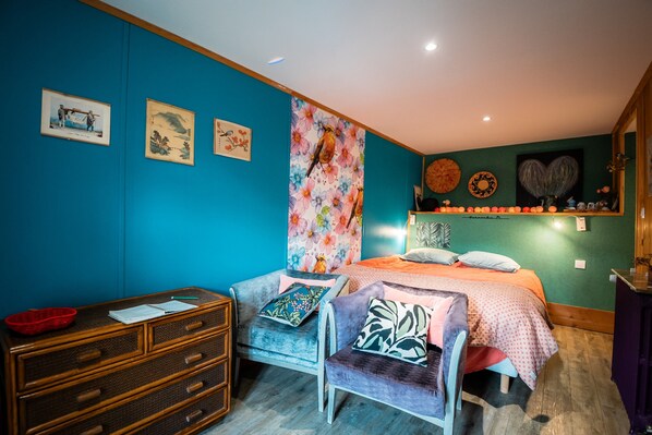 Une pièce comprenant un lit, une chaise, une commode et des œuvres d’art mural.