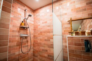 Une salle de bain avec une douche, des murs carrelés, un miroir et un porte-serviettes.
