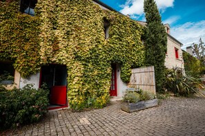 Un bâtiment aux murs recouverts de lierre, avec une porte rouge et un chemin pavé.