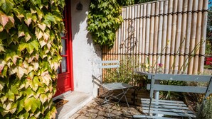 A patio with a metal table and chairs, a bamboo fence, and a red door.