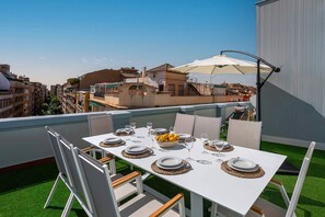 A rooftop terrace with a white table set for four, surrounded by white chairs, a large umbrella, and a view of the cityscape. - Exclusive Penthouse With Private Terrace in Granada San Anton 402 (Granada)
