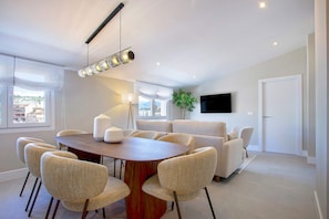 A modern living room with a dining area, a sofa set, a flat-screen TV, and a large window. - Exclusive Penthouse With Private Terrace in Granada San Anton 402 (Granada)