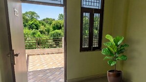 Una puerta abierta que da a un balcón con una planta en maceta.