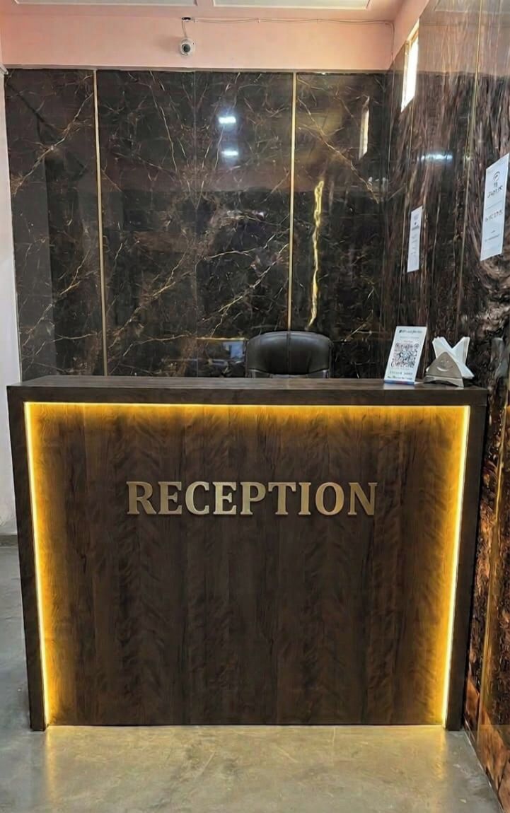 Un mostrador de recepción con una pared de mármol y un cartel que dice 'RECEPTION'.