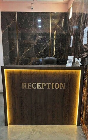 Un mostrador de recepción con una pared de mármol y un cartel que dice 'RECEPTION'.