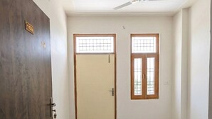 Una habitación con una puerta de madera, una puerta color beige y una ventana con diseño de cuadrícula.