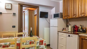 Une cuisine compacte comprenant une table à manger, des placards en bois, un four à micro-ondes et un réfrigérateur.