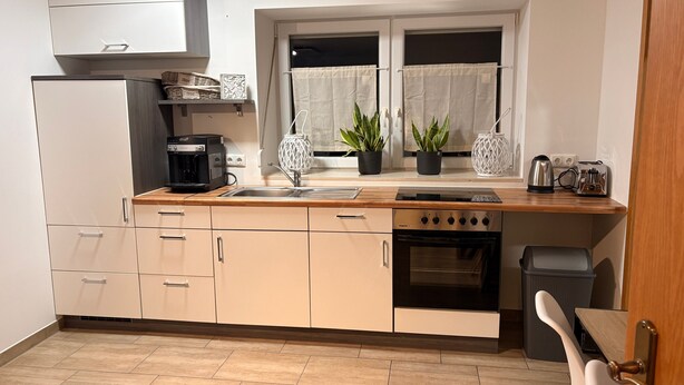A kitchen with a coffee maker, oven, and two potted plants. - Cozy 60 m² Apartment with Terrace (Künzing)