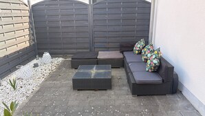 A patio with a sofa set, cushions, a lantern, and a small garden area. - Cozy 60 m² Apartment with Terrace (Künzing)