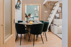 Un coin repas avec une table ronde, des chaises vert foncé et un vase rempli de fleurs.