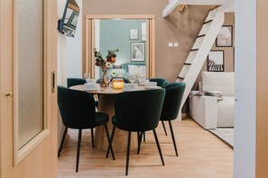 Un coin repas avec une table ronde, des chaises vert foncé et un vase rempli de fleurs.