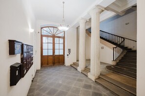 Un couloir avec une porte en bois, un escalier et un luminaire.