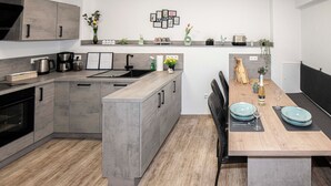 Una cocina moderna con armarios grises, una mesa de comedor de madera y una isla integrada.