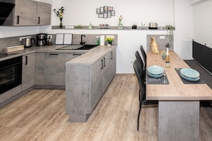 A modern kitchen with grey cabinetry, a wooden dining table, and a built-in island.