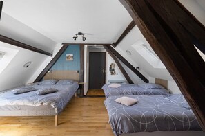 A bedroom with two beds, wooden flooring, a sloped ceiling, and a small desk with a chair. - Guest Room 'La Ferme Des Bigornes - Lion' with Shared Terrace, Garden & Wi-Fi (Châtillon-sur-Indre)