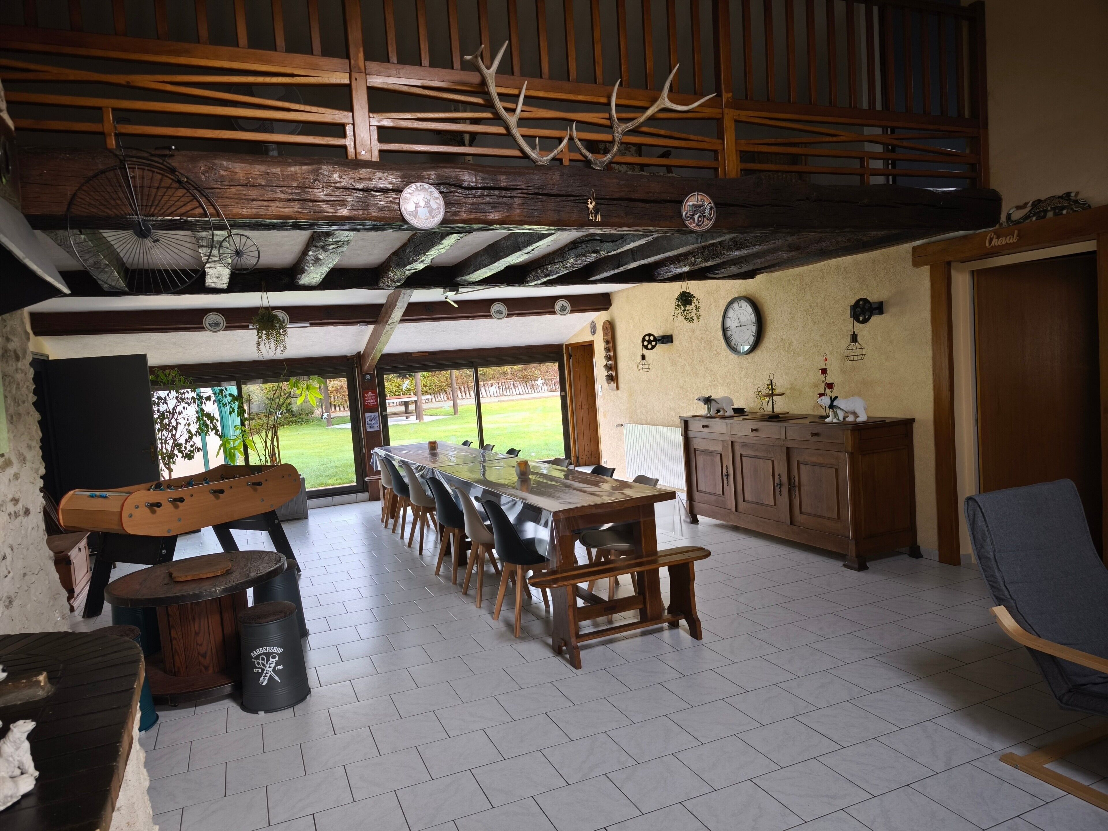 A spacious dining area with a long table, wooden chairs, a bench, and a view of the outdoors.