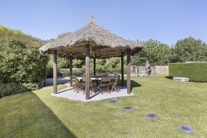 A gazebo with a thatched roof, surrounded by a well-maintained lawn and trees. - Guest Room 'La Ferme Des Bigornes - Lion' with Shared Terrace, Garden & Wi-Fi (Châtillon-sur-Indre)