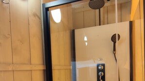 A glass-enclosed shower with a handheld showerhead and a wall-mounted faucet. - Anna Glamping (Anna)