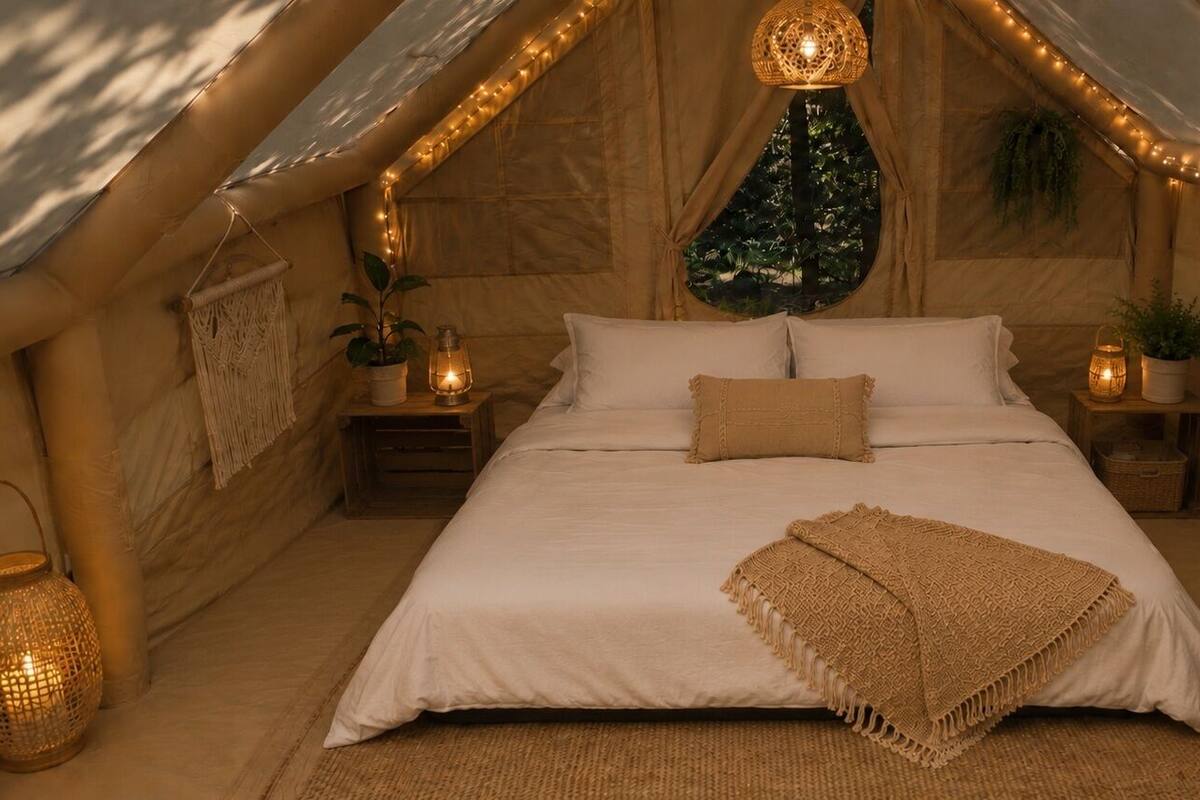 A cozy tented room with a bed, string lights, and a hanging light fixture.