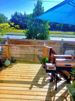 A wooden deck with a barbecue grill and a potted plant. - Cozy basement apartment (Kitchener)