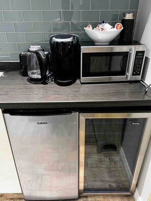 Cozinha equipada com cafeteira, micro-ondas e máquina de lavar lou ça.