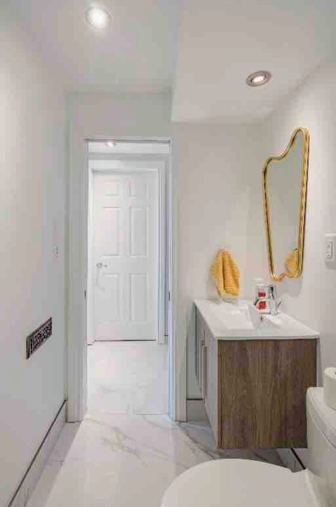 A bathroom with a white vanity, a mirror, and a toilet.
