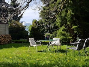 Ein Garten mit Tisch und Stühlen, einem Blumentopf und einem Holzstapel.