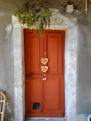 A red door with heart-shaped decorations, a small pet door, and a hanging plant above. - Guest Room “L'oie” with Garden View and Wi-Fi (Onnion)