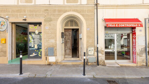 A building with a shop entrance, a visible door, and a red awning with signage. - Apartment 'Terraviva - La Terrazza Sul Nespolo' with Private Terrace, Wi-Fi and Air Conditioning (Cecina)