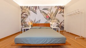 A bedroom with a bed, a nightstand, a lamp, and a wall-mounted drying rack. - Apartment 'Terraviva - La Terrazza Sul Nespolo' with Private Terrace, Wi-Fi and Air Conditioning (Cecina)