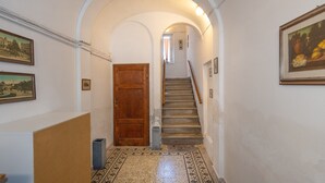 A hallway with a wooden door, a staircase, and a tiled floor. - Apartment 'Terraviva - La Terrazza Sul Nespolo' with Private Terrace, Wi-Fi and Air Conditioning (Cecina)