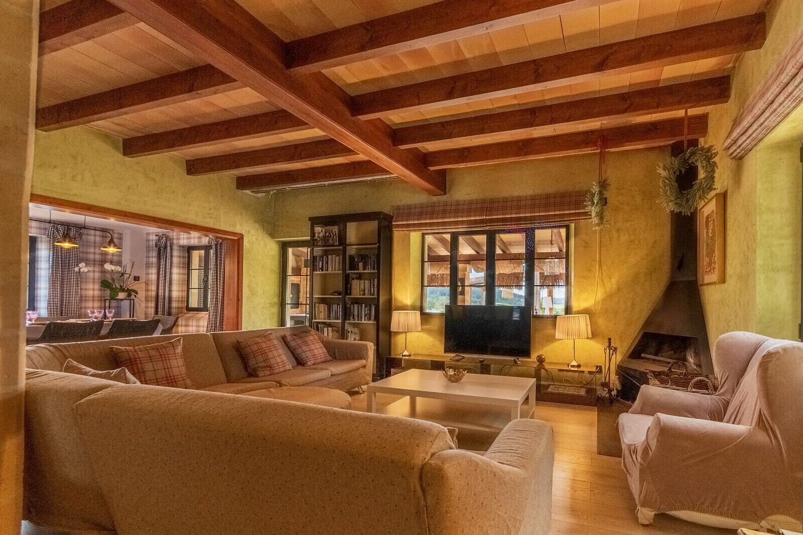 A cozy living room with a sofa, armchairs, a coffee table, a bookshelf, and a fireplace.
