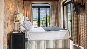 Un dormitorio con un ventanal grande, una cama con colcha a rayas, una lámpara de noche y vistas al exterior.