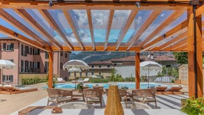A covered outdoor area with a pool, lounge chairs, and a pergola structure. - Appartamento The Rich Man (Bellagio)