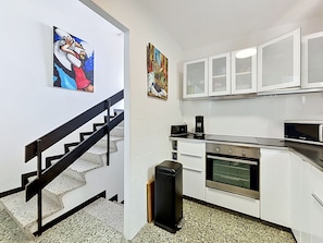 A kitchen with white cabinets, a black countertop, a coffee maker, and a microwave. - CASA BARBARA Roses / Roses - INTERimmo (Rosas / Roses)
