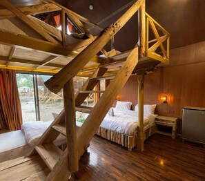 Une pièce avec un escalier en bois, un lit, une table de chevet et une fenêtre.
