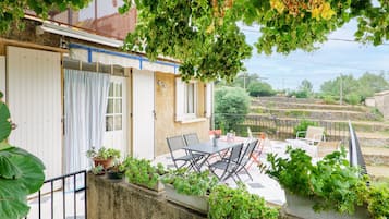 Asuinrakennus, jossa on patio, ulkotila istumista varten ja ruukkukasveja.