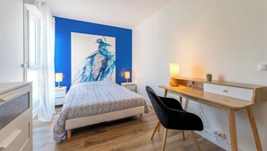 A bedroom with a bed, a desk, a chair, and a large painting on the wall. - Companies, large families, free parking (ROUEN)