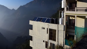 Un hôtel avec une enseigne indiquant son nom, des panneaux solaires sur le toit et une vue sur les montagnes en arrière-plan.
