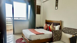Une chambre d’hôtel avec un lit, un canapé, une fenêtre et un balcon.